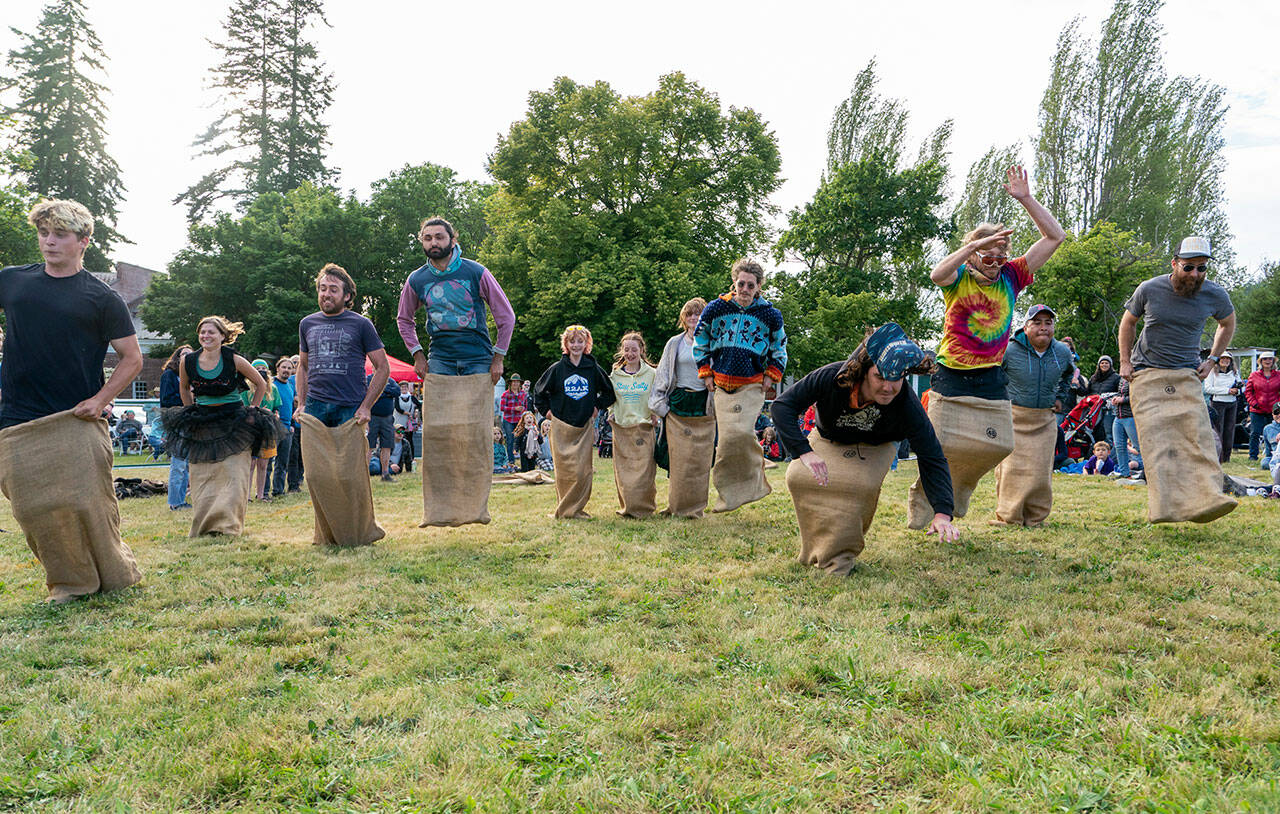 Adults compete in a sack race during activities at the Field Day event at Fort Worden State Park on Saturday. (Steve Mullensky/for Peninsula Daily News)