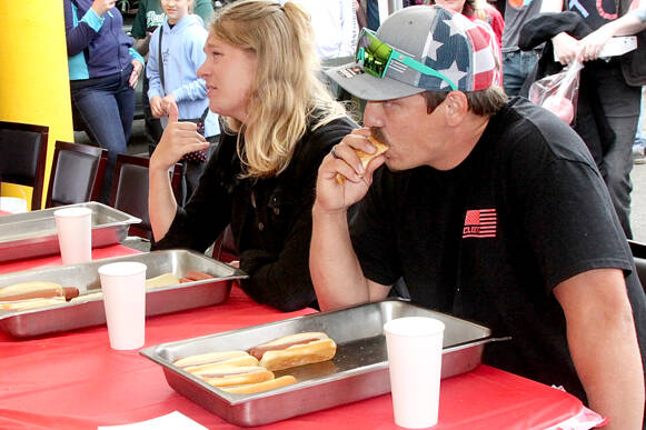 Brandon Elliott, right, of Port Angeles, ate 7 1/2 hot dogs to win a contest Monday next to the Wharf in downtown Port Angeles. Richard Wright, left, of Port Angeles finished second and K.T. Nall of Santa Barbara, Calif., placed third. (Dave Logan/for Peninsula Daily News)