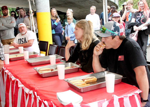 Brandon Elliott, right, of Port Angeles, ate 7 1/2 hot dogs to win a contest Monday next to the Wharf in downtown Port Angeles. Richard Wright, left, of Port Angeles finished second and K.T. Nall of Santa Barbara, Calif., placed third. (Dave Logan/for Peninsula Daily News)