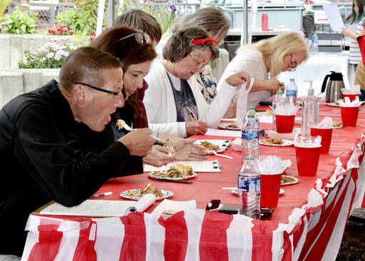Cory Delicate, left, of Port Angeles tests one of the 26 apple pies alongside a panel of six judges.  (Dave Logan/for the Peninsula Daily News)