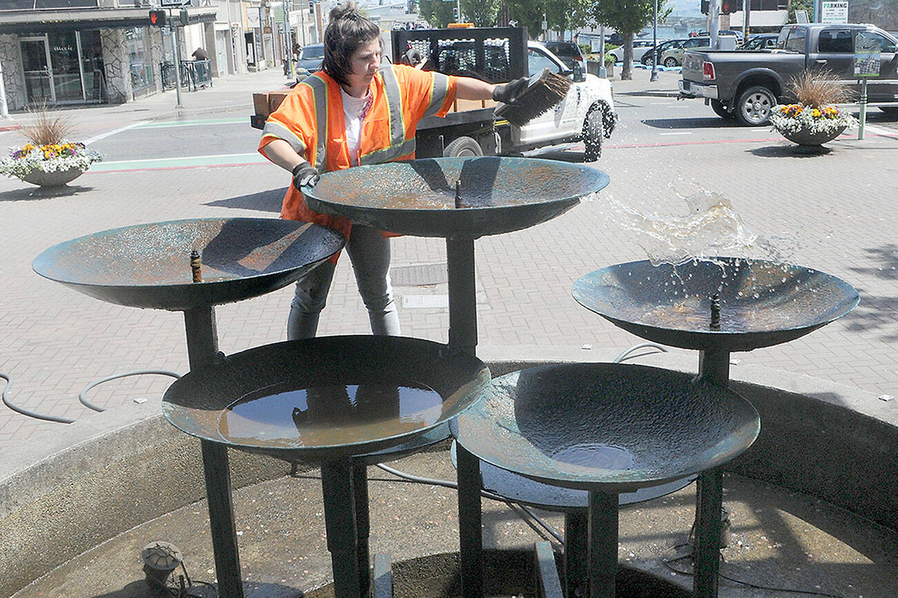 Keith Thorpe/Peninsula Daily News
Destiny Walters of the Port Angeles Parks and Recreation Department scrubs the water bowls on the Conrad Dyar Memorial Fountain in downtown Port Angeles. The fountain and its adjoining plaza, located at First and Laurel streets, is a focal point for numerous activities in the downtown area.