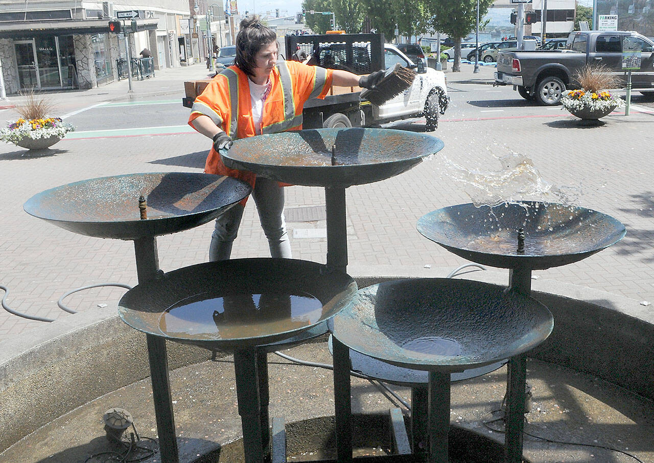 Destiny Walters of the Port Angeles Parks and Recreation Department scrubs the water bowls on the Conrad Dyar Memorial Fountain in downtown Port Angeles. (Keith Thorpe/Peninsula Daily News)
