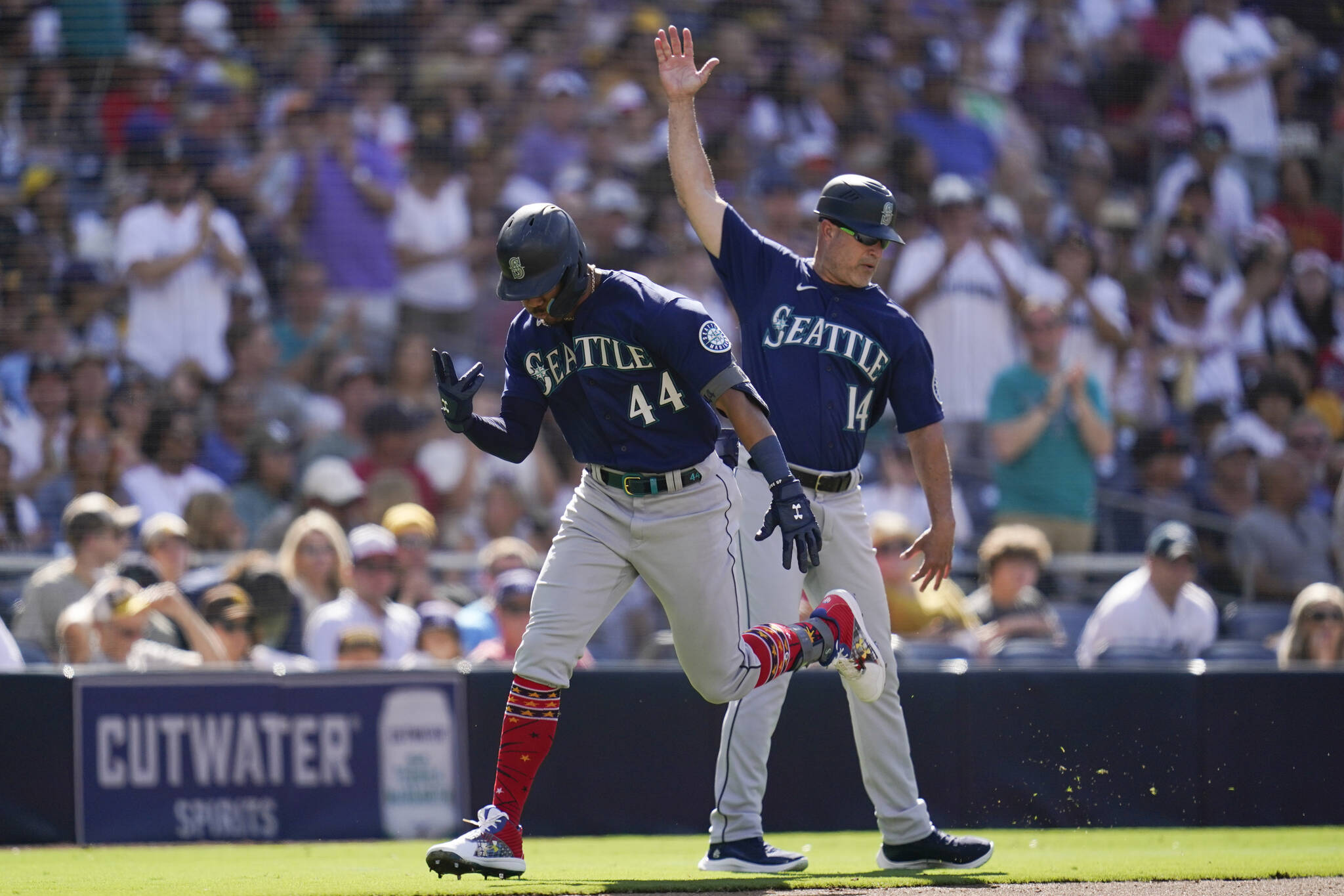 The Seattle Mariners’ Julio Rodriguez, left, reacts with third base coach Manny Acta after hitting a two-run home run during the fourth inning of a baseball game against the San Diego Padres on Monday in San Diego. (Gregory Bull/The Associated Press)