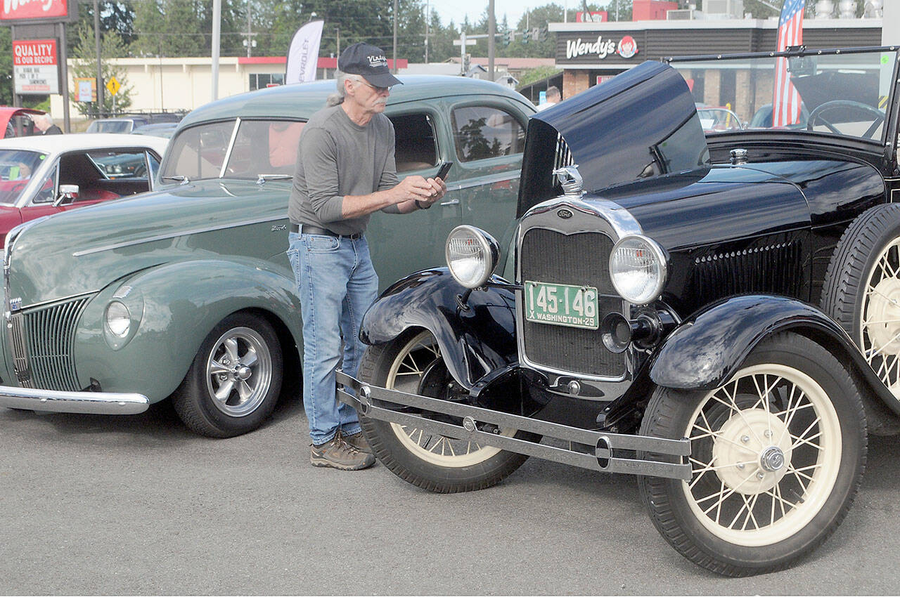 David Johannessohn of Sequim takes a photograph of the motor of a 1929 Ford Model A on Saturday at the 26th annual Ruddell Cruise-In car show at Ruddell Auto in Port Angeles. The event featured more than 200 vintage and classic automobiles and trucks in an evening that included food, live music and a dunk tank. (Keith Thorpe/Peninsula Daily News)