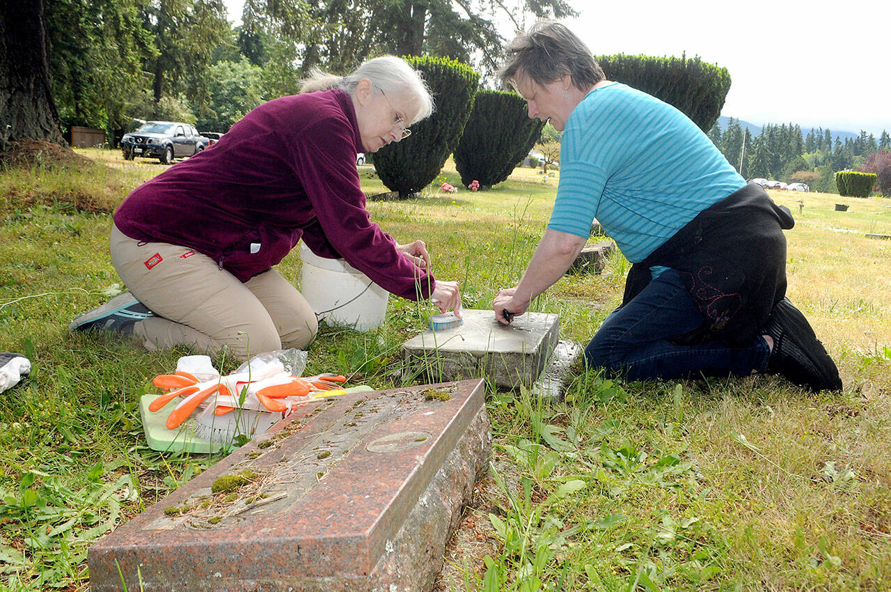 Volunteers Ginger Sanford, left, and Vicki Hansen, both of Port Angeles, carefully scrub a military veterans headstone at Mount Angeles Memorial Park in Port Angeles on Saturday. The Michael Trebert Chapter of the Daughters of the American Revolution hosted a training seminar and workshop on the do no harm method cleaning and preserving grave markers. The workshop was held in preparation for a Wreaths Across American Wreath Laying ceremony scheduled for Dec. 17. (Keith Thorpe/Peninsula Daily News)
