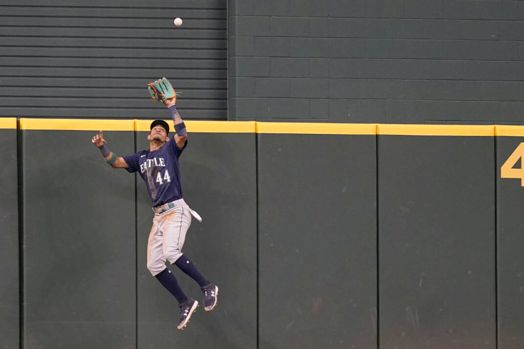 Seattle Mariners center fielder Julio Rodriguez (44) jumps to catch a fly out at the wall against Texas Rangers Adolis Garcia during the second inning of a baseball game in Arlington, Texas, Sunday, July 17, 2022. (AP Photo/LM Otero)