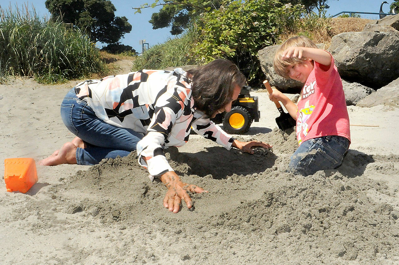 Five-year-old Barron Strangle, right, reacts as his grandmother, Ellen Mack, buries him thigh-deep in a hole they excavated at Hollywood Beach in Port Angeles on Tuesday. The pair, both from Port Angeles, were taking advantage of a sunny summer day on the sand. (Keith Thorpe/Peninsula Daily News)