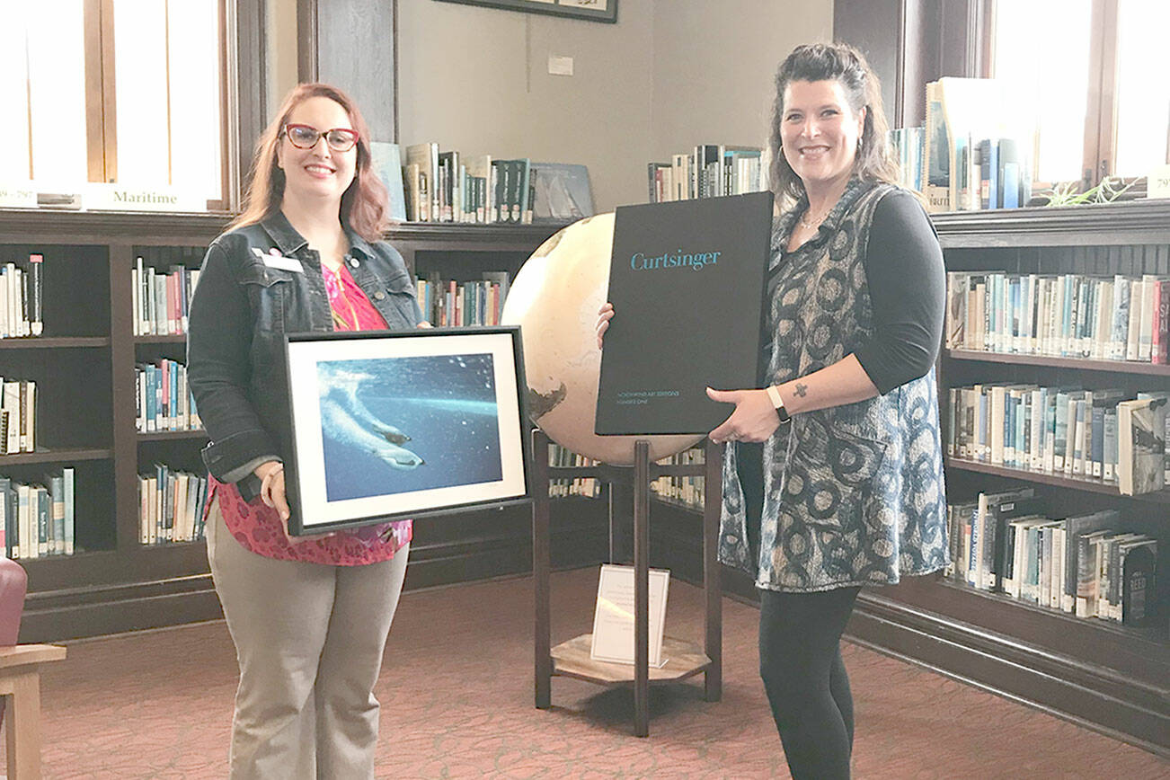 Melody Sky Weaver, on left, accepts a donated Bill Curtsinger photograph from Teresa Verraes, executive director of Northwind Art.