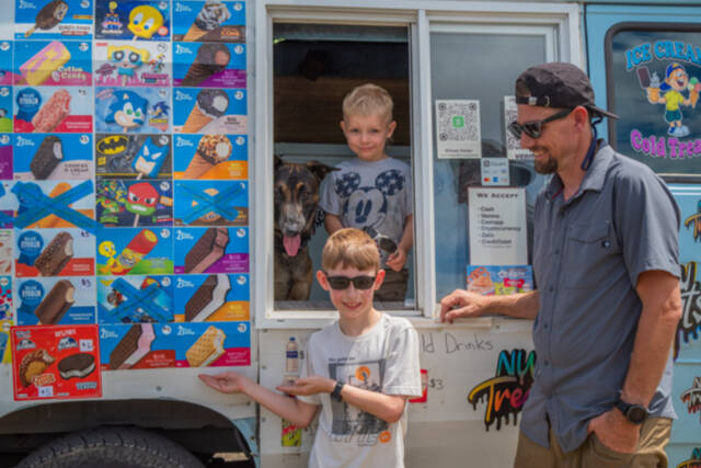 From left to right, Mr. Orange and Justin, Charlie and Joe Parker pause inside and outside their ice cream truck in Sequim. Northwest Treats has no fixed route, but travels all over Sequim and Port Angeles and in between and as far as Lake Sutherland and the lower Elwha. Joe Parker says that “people message us to come by,” using text, instagram and Facebook.  Emily Matthiessen/Olympic Peninsula News Group