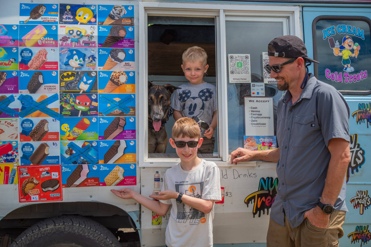 From left to right, Mr. Orange and Justin, Charlie and Joe Parker pause inside and outside their ice cream truck in Sequim. Northwest Treats has no fixed route, but travels all over Sequim and Port Angeles and in between and as far as Lake Sutherland and the lower Elwha. Joe Parker says that “people message us to come by,” using text, instagram and Facebook. (Emily Matthiessen/Olympic Peninsula News Group)