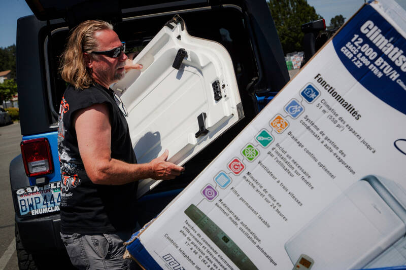 Brian Gadzuk, 56, clears out the trunk of his Jeep to make space for a new air conditioning unit in the parking lot at McLendon Hardware in Renton on Sunday. The Pacific Northwest is bracing for a major heat wave, with temperatures forecast to top 100 degrees in some places this week as climate change fuels longer hot spells in a region where such events were historically uncommon. (Kori Suzuki/The Seattle Times via AP)