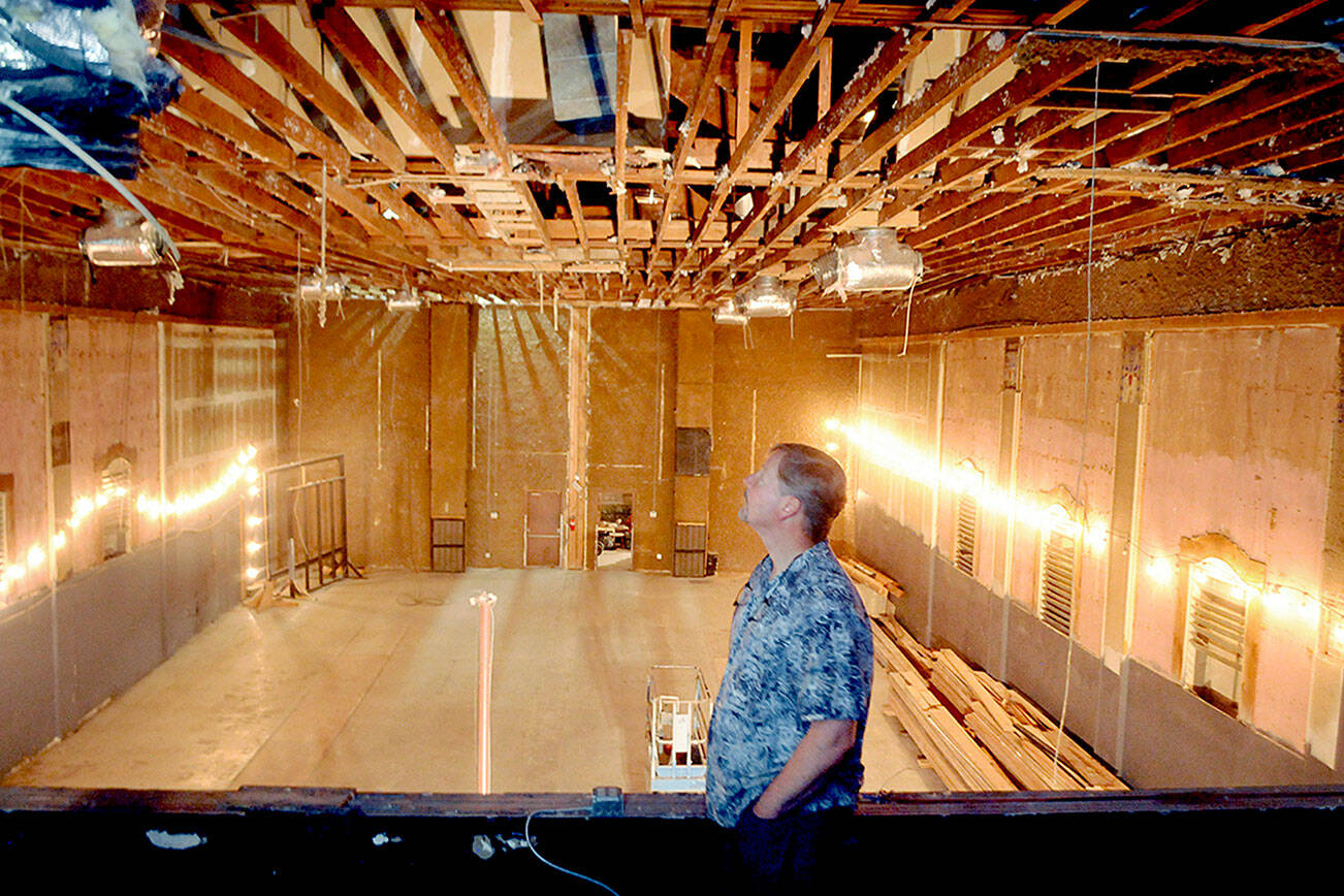 Lincoln Theater co-owner Marty Marchant looks at the exposed rafters of the theater on Saturday after they were uncovered by workers who removed the ceiling the previous week. (Keith Thorpe/Peninsula Daily News)