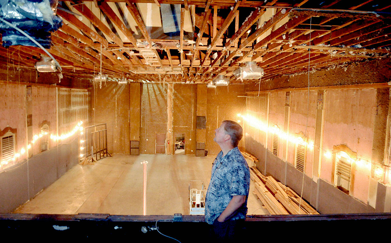 Lincoln Theater co-owner Marty Marchant looks at the exposed rafters of the theater on Saturday after they were uncovered by workers who removed the ceiling the previous week. (Keith Thorpe/Peninsula Daily News)