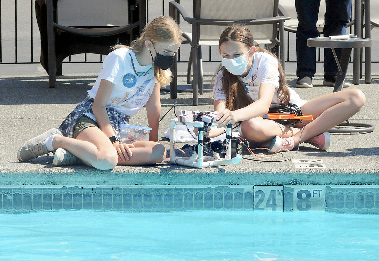 Remotely operated vehicle teammates Stella Fradkin, left, and Cate Chance, both 12 from Port Angeles, make final adjustments to their underwater craft before competing in an obstical course on Friday at the swimming pool of the Red Lion Hotel in Port Angeles. (Keith Thorpe/Peninsula Daily News)