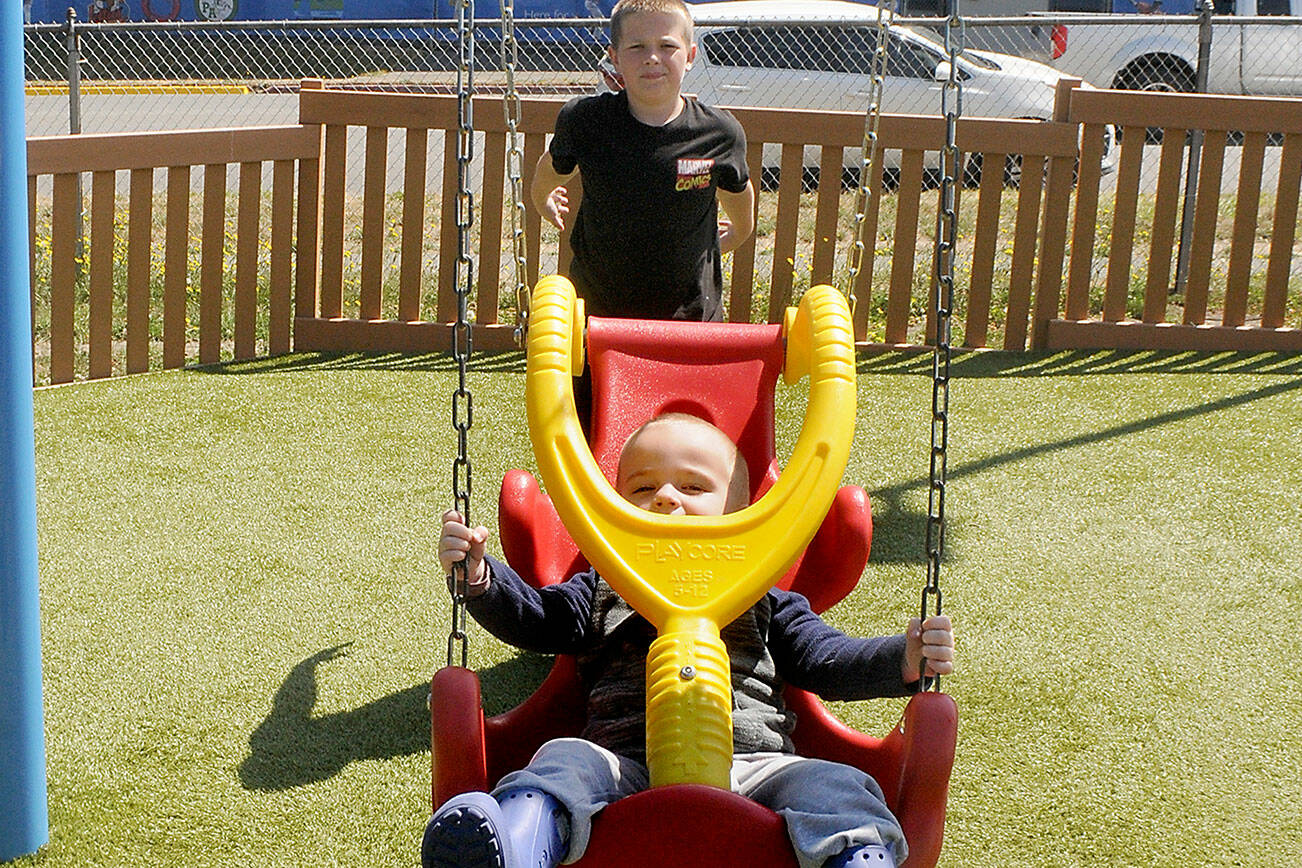 Liam Owens of Sequim, 11, pushes his brother, Kamden Owens, 2 1/2, on a swing at the Dream Playground at Erickson Playfield in Port Angeles. The pair were among dozens of children taking advantage of the year-old volunteer-built playground. (Keith Thorpe/Peninsula Daily News)