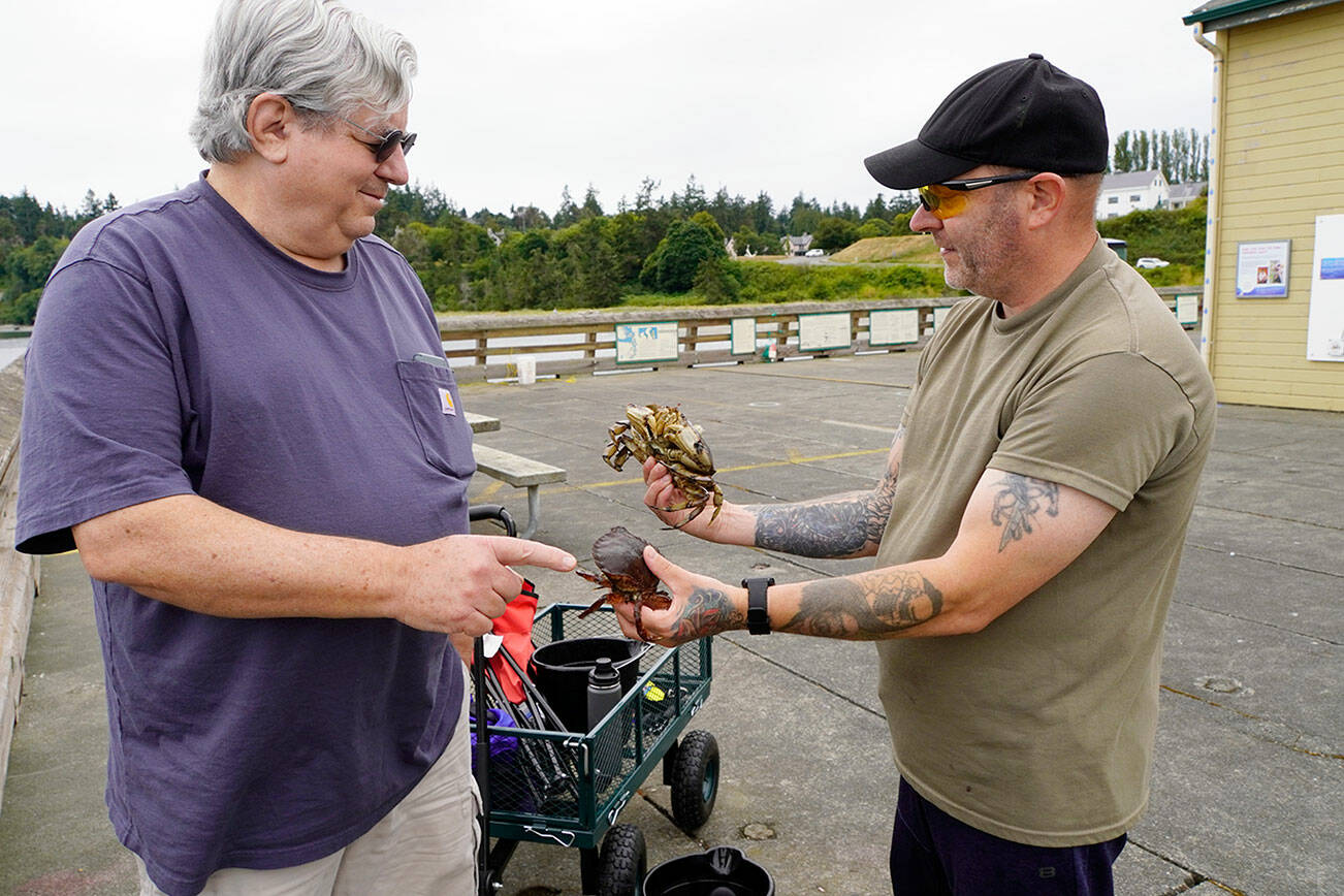 Scott Miller, left, of Silverdale points to the undersized rock crab that Tom Price of Spanaway is holding. Both men were crabbing off the Marine Science Center pier at Fort Worden on Thursday. The other crab was barely legal size, and Price put both back into the sea. (Steve Mullensky/for Peninsula Daily News)