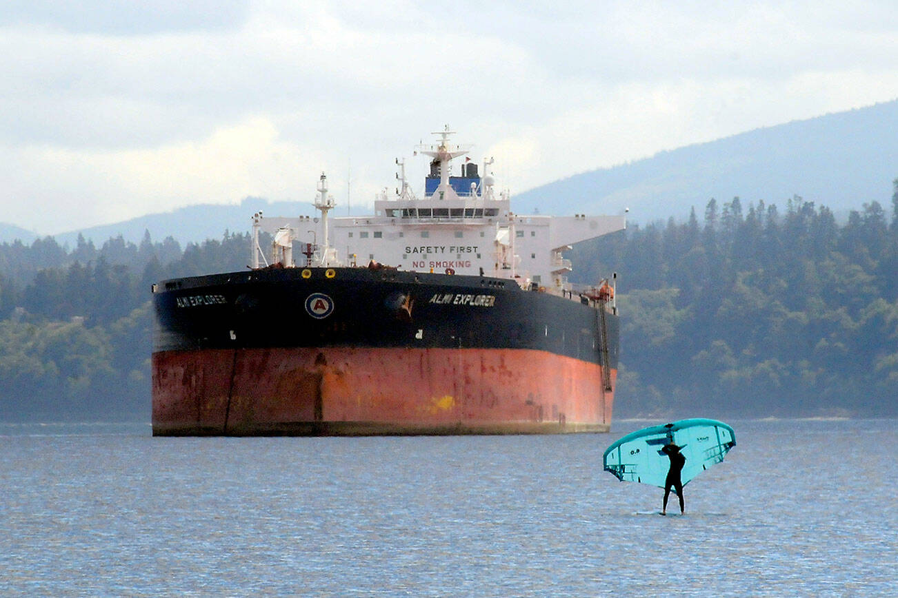 Keith Thorpe/Peninsula Daily News
A wind foiler makes their way across the waters of Port Angeles Harbor against a backdrop of the tanker ship Almi Explorer. Moderate breezes from the Strait of Juan de Fuca made for pleasant conditions for wind-driven sports.