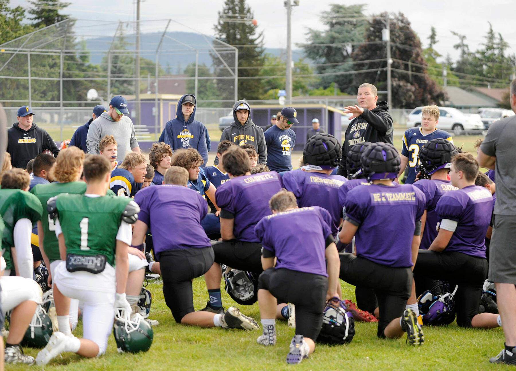 Sequim football coach Erik Wiker speaks to Sequim, Port Angeles and Forks players at a three-team scrimmage in 2018. Sequim players can be seen wearing Guardian Caps on their helmets. (Michael Dashiell/Olympic Peninsula News Group)