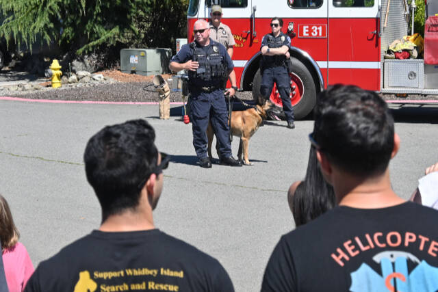 Sequim Gazette photo by Michael Dashiell / Kevin Miller, Port Angeles Police Department officer, offers a K-9 demonstration as Kitsap County Sheriff's Office deputy Aaron Baker. and Port Angeles police officer Whitney Fairbanks look on.