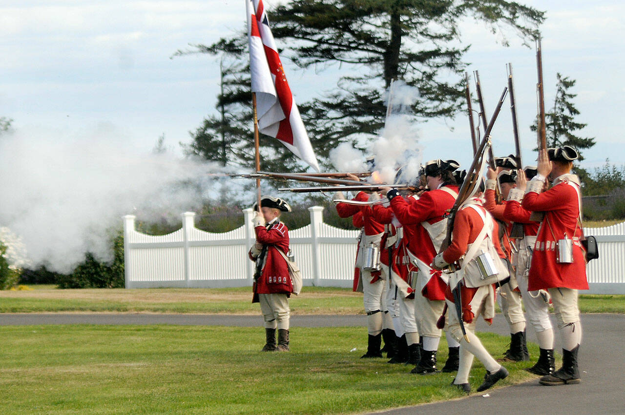 A group of Revolutionary War re-enactors, playing part of British soldiers, fire their guns during a mock battle during the 2022 NW Colonial Festival at the George Washington Inn and Estate near Agnew. (Keith Thorpe/Peninsula Daily News)