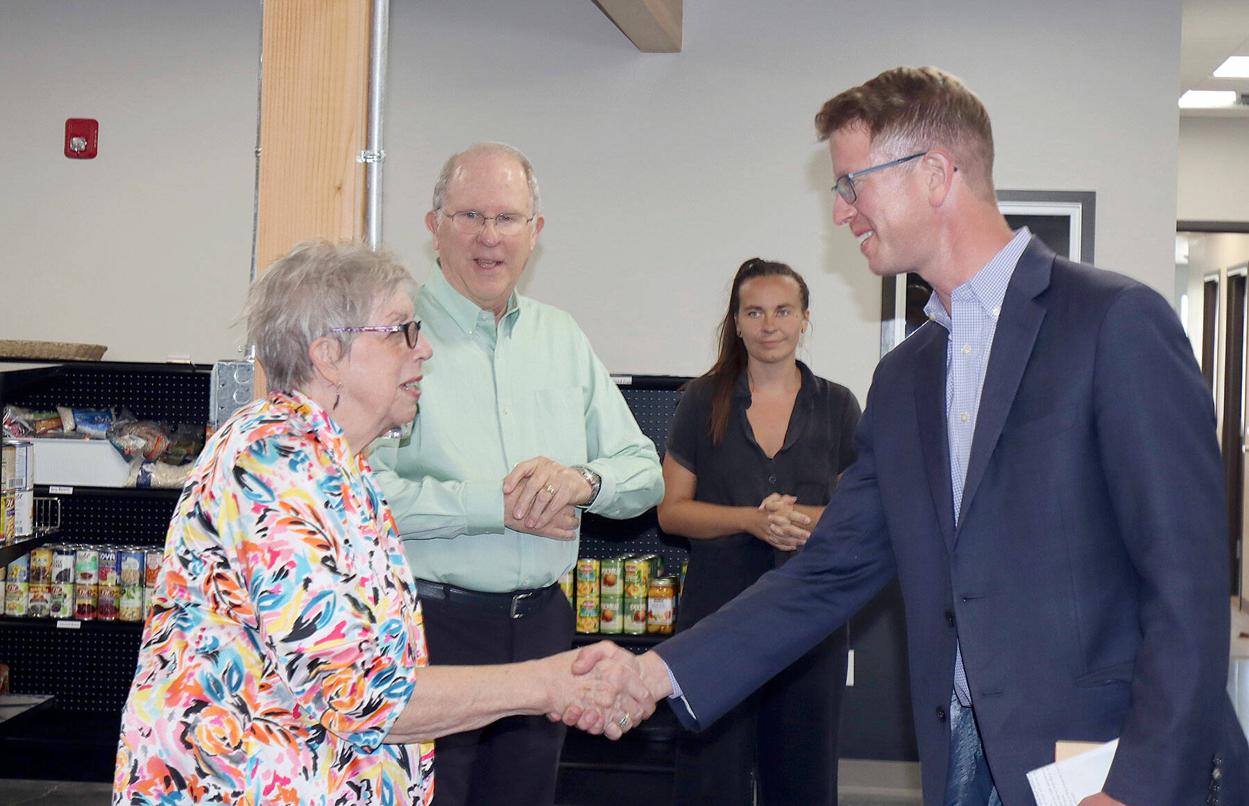U.S. Rep. Derek Kilmer shakes hands with Diana Walter-Lopez, Port Angeles Food Bank board secretary. Behind her is Kelly Fisher, board treasurer. In the background is Alexi Nelson of the Food Bank staff. (Dave Logan/for Peninsula Daily News)