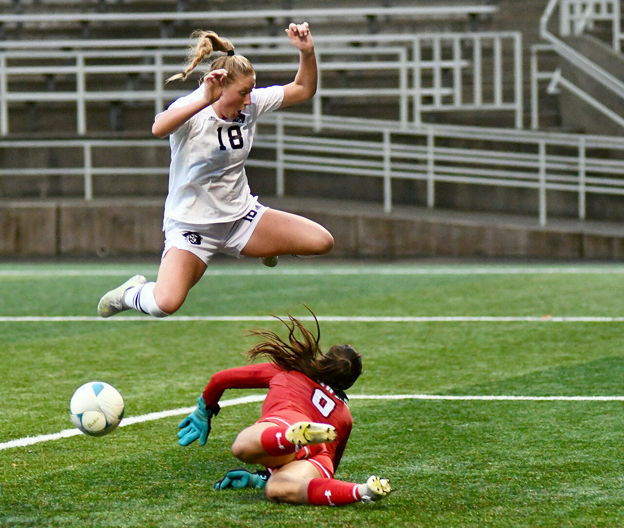 Jay Cline/for Peninsula College Peninsula College’s Kyrsten McGuffey hurdles Columbia Basin goalkeeper RiaJo Schwartz during the first half of the Pirates 2-1 come-from-behind win over the Hawks in the NWAC Semifinals on Friday at Starfire Sports Stadium.