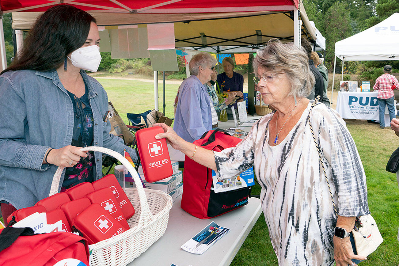 Carol Riley of Port Ludlow receives a free first aid kit from Apple Martine, director of Jefferson County Public Health, during the emergency preparedness demonstrations at HJ Carroll Park in Chimacum on Saturday. (Steve Mullensky/for Peninsula Daily News)