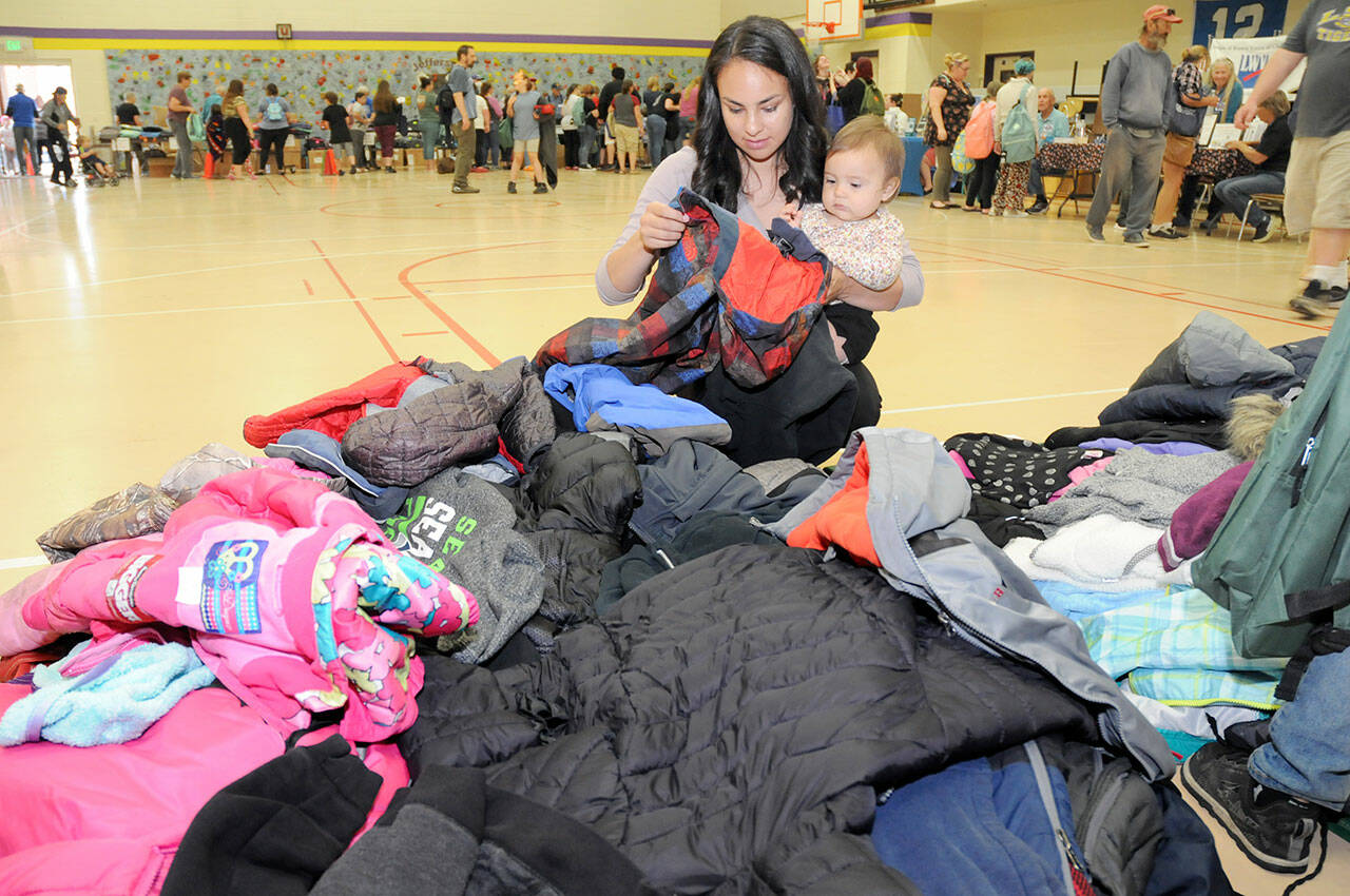 Heidi Eberle of Port Angeles and her daughter, Akira Abbitt, 11 months, sort through a stack of free children’s coats during Saturday’s Port Angeles School District Back to School Fair at Jefferson Elementary School. (Keith Thorpe/Peninsula Daily News)