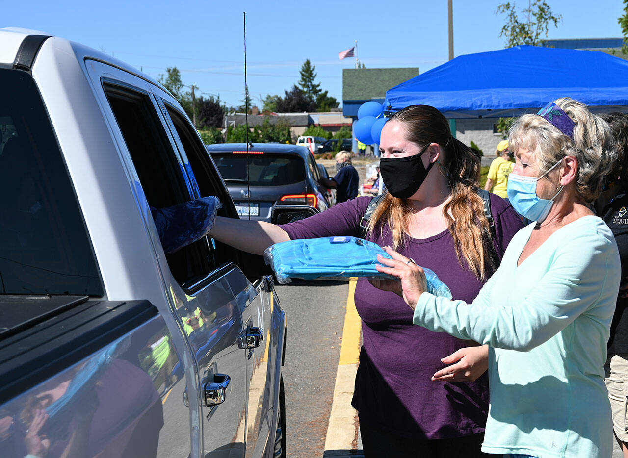 Rachel Tax, left, and Karen Kremkau hand out backpacks at the Back to School Fair at Helen Haller Elementary in 2021. Saturdays event features a drive-through and on-the-field fair at the Sequim School District stadium on West Fir Street. (Michael Dashiell / Olympic Peninsula News Group)
