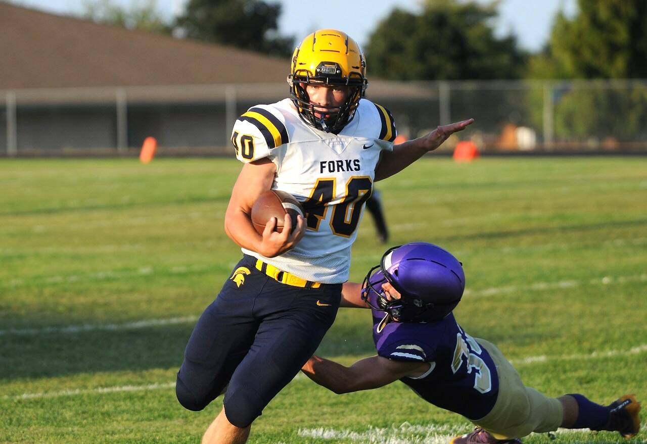 Forks running back Nate Dahlgren looks to avoid Sequim linebacker Sam Fitzgerald in the first half of Forks' 32-14 non-league win over the Sequim Wolves on Friday night. (Michael Dashiell/Olympic Peninsula News Group)