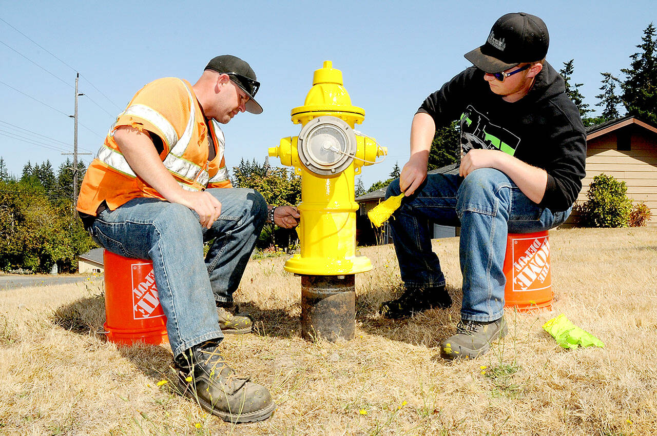 Port Angeles Water Utility workers Garey Hampton, left, and Logan Beebe apply a new coat of paint to a fire hydrant near the corner of 12th and I streets on a warm Friday in Port Angeles. (Keith Thorpe/Peninsula Daily News)