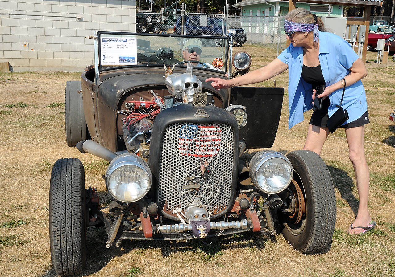 Julie Moen of Port Angeles, right, points the quirks of a “rat rod” built from a 1928 Ford Roadster by Dennis Broderson of Port Angeles, in drivers seat, during Saturday’s Kiwanis Car Show at the Clallam County Fairgrounds in Port Angeles. (Keith Thorpe/Peninsula Daily News)