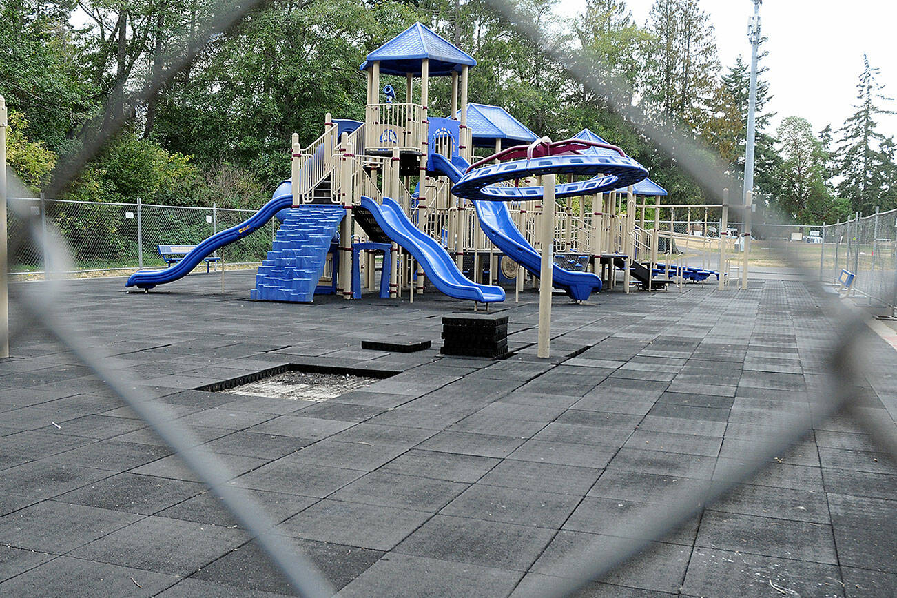 Fencing surrounds the playground at Shane Park in Port Angeles after parks department officials closed the equipment because of play surface tiles that are shrinking and becoming dislodged. (Keith Thorpe/Peninsula Daily News)