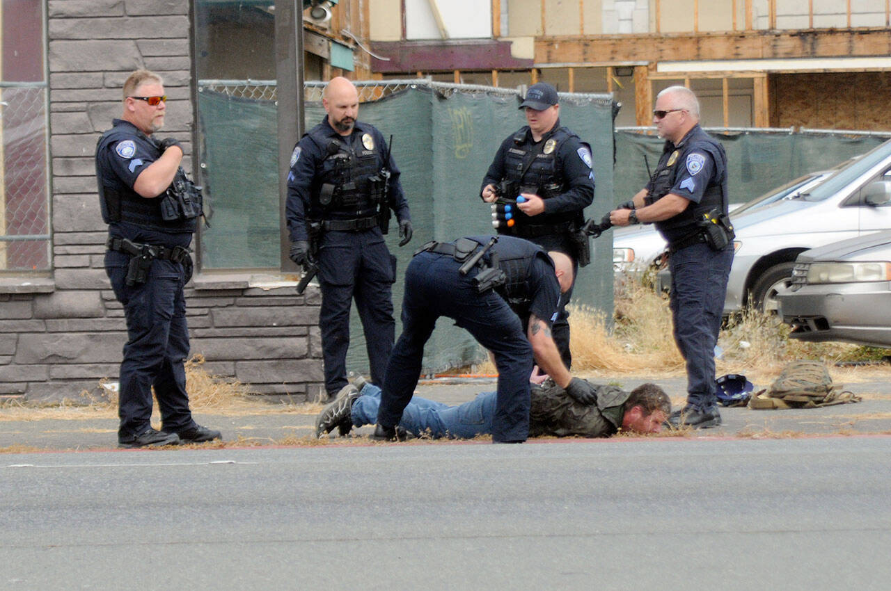 Port Angeles police arrest a man at the corner of First and Albert streets in Port Angeles on Tuesday after he allegedly created a disturbance and brandished a handgun replica at passers-by. (Keith Thorpe/Peninsula Daily News)