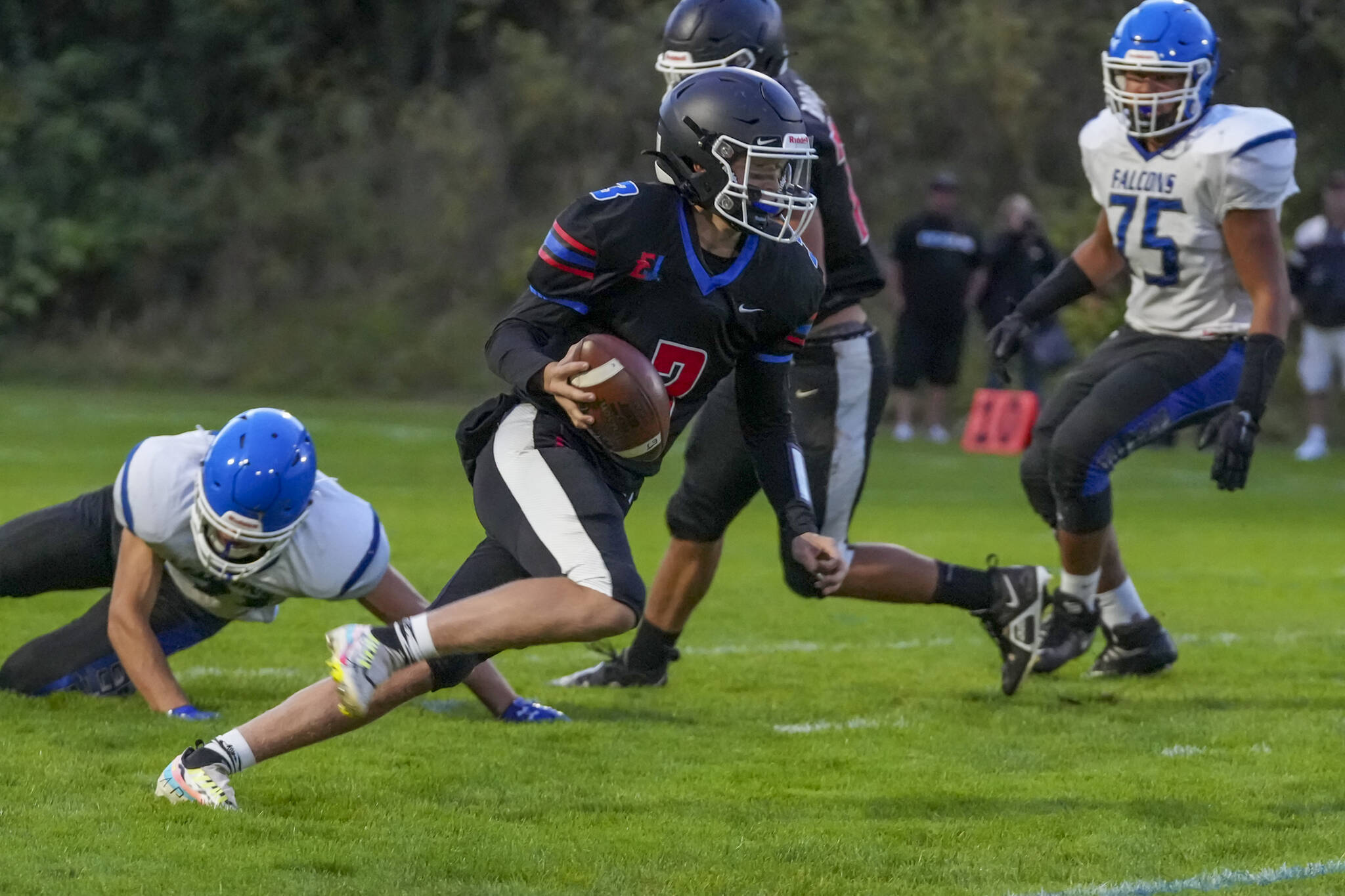 Rivals’ QB Cash Holmes eludes a South Whidbey defender and looks for a receiver downfield during a game Friday night at Memorial Field in Port Townsend.