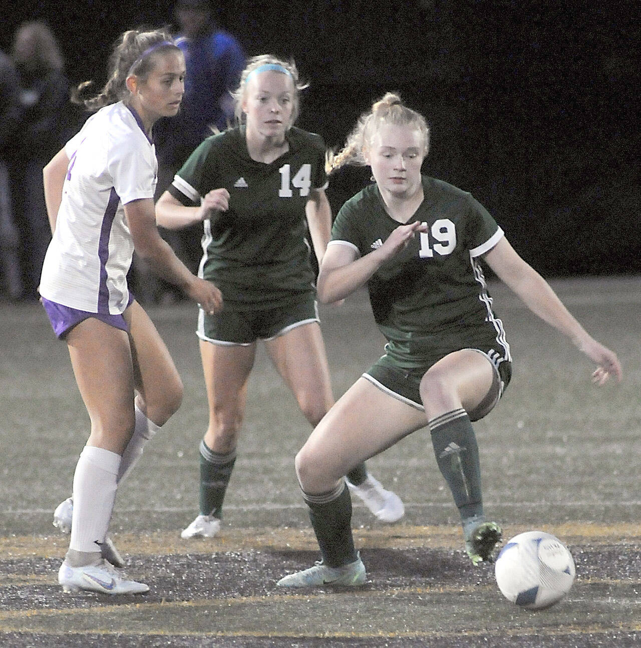 Port Angeles’ Paige Mason, right, slips past North Kitsap’s Syleena Hogan, left, as teammate Anna Petty looks on during Tuesday’s match at Peninsula College. (Keith Thorpe/Peninsula Daily News)