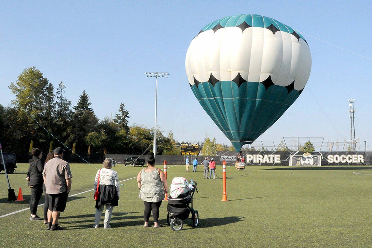 A hot air balloon rises from the soccer field of the Wally Sigmar Athletic Complex at Peninsula College in Port Angeles for tethered rides on Saturday as part of the Peninsula College Fall Spectacular. The event, hosted by the school to bring the community to the campus, also featured displays and demonstrations, children’s activities, food and music. (Keith Thorpe/Peninsula Daily News)