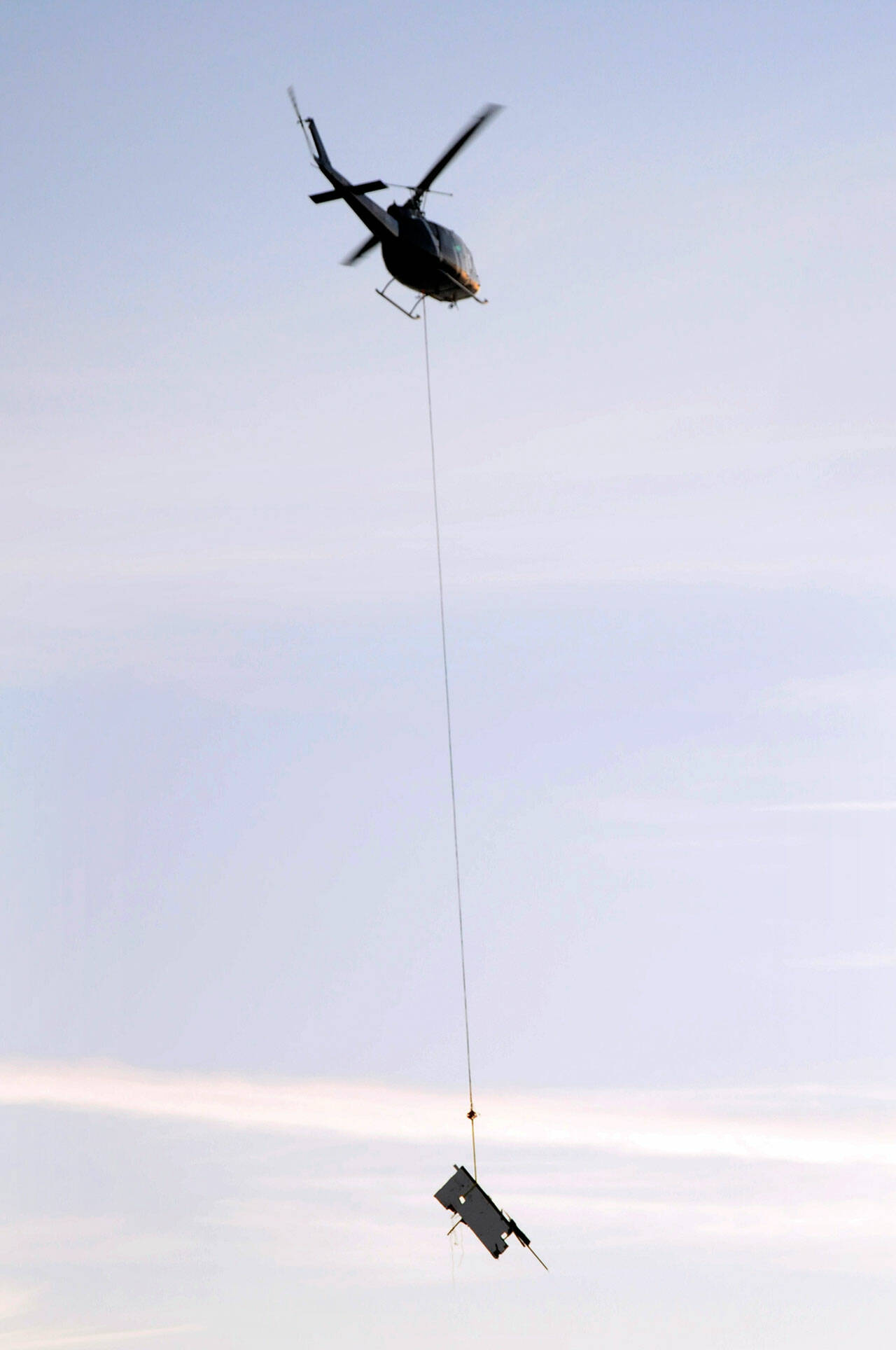 A piece of the cabin cruiser Eudora is lifted by helicopter to a staging area after it was hoisted from the beach on Ediz Hook on Wednesday. (Keith Thorpe/Peninsula Daily News)
