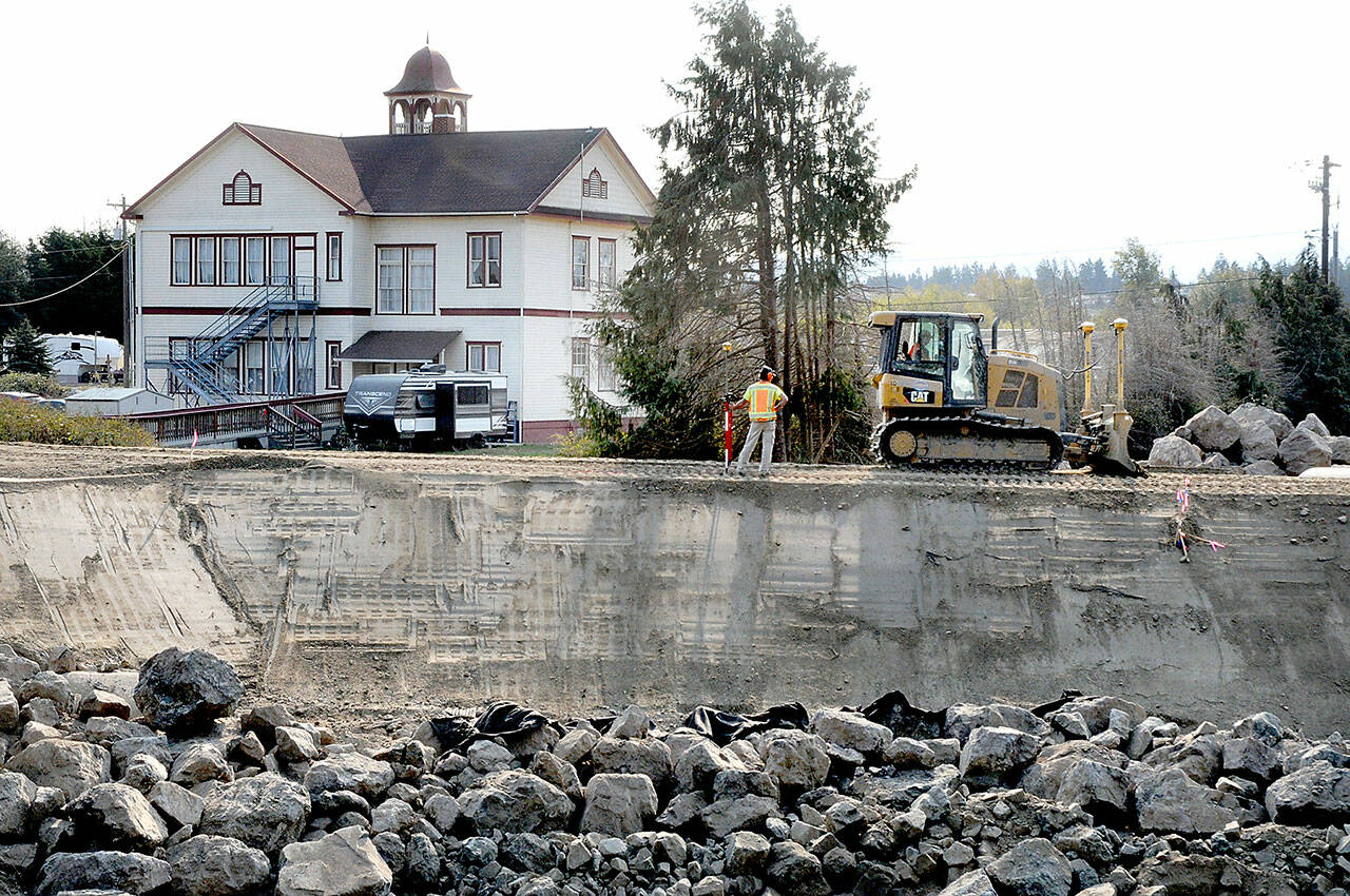 A bulldozer levels dirt along a new levee being built along the Dungeness River on Saturday not far from the mouth of the river near the Dungeness community north of Sequim. The first phase of the multi-year levee setback project includes construction of a new levee and an embankment to realign Towne Road, as well as culverts and restoration of the rivers floodplain. In the background is the historic Dungeness Old Schoolhouse. (Keith Thorpe/Peninsula Daily News)