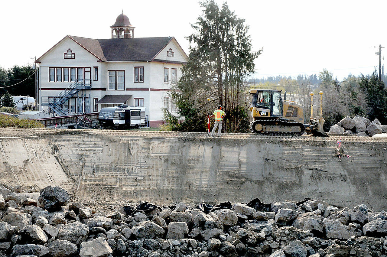 A bulldozer levels dirt along a new levee being built along the Dungeness River on Saturday not far from the mouth of the river near the Dungeness community north of Sequim. The first phase of the multi-year levee setback project includes construction of a new levee and an embankment to realign Towne Road, as well as culverts and restoration of the river’s floodplain. In the background is the historic Dungeness Old Schoolhouse. (Keith Thorpe/Peninsula Daily News)