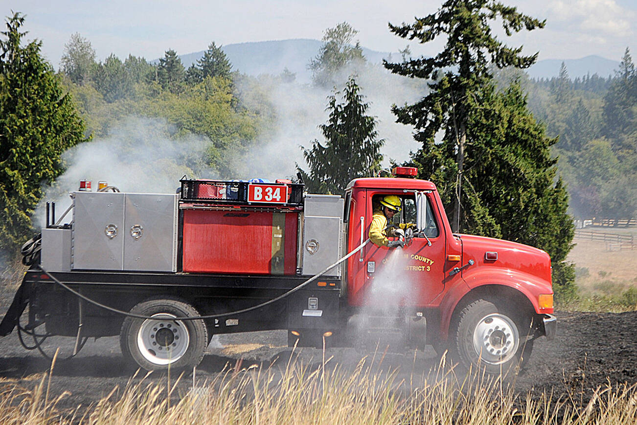 Officials with Clallam County Fire District 3 plan to make a decision in 2023 whether or not to go to voters to approve more funding to add staff, apparatuses and/or new fire stations. Here, firefighters fight a brush fire in July 2021 west of Sequim. (Matthew Nash/Olympic Peninsula News Group)