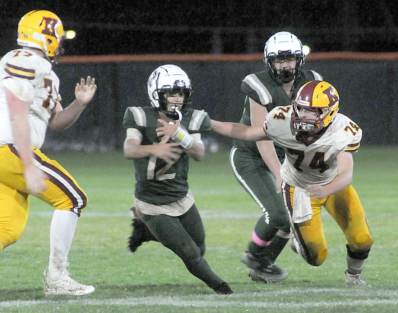 Port Angeles’ Kason Albaugh, center, runs between Kingston’s Tyler Rose, left, and Jackson Glammeier, right, as teammate Hunter Flores looks on from behind on Friday night in Port Angeles. (Keith Thorpe/Peninsula Daily News)