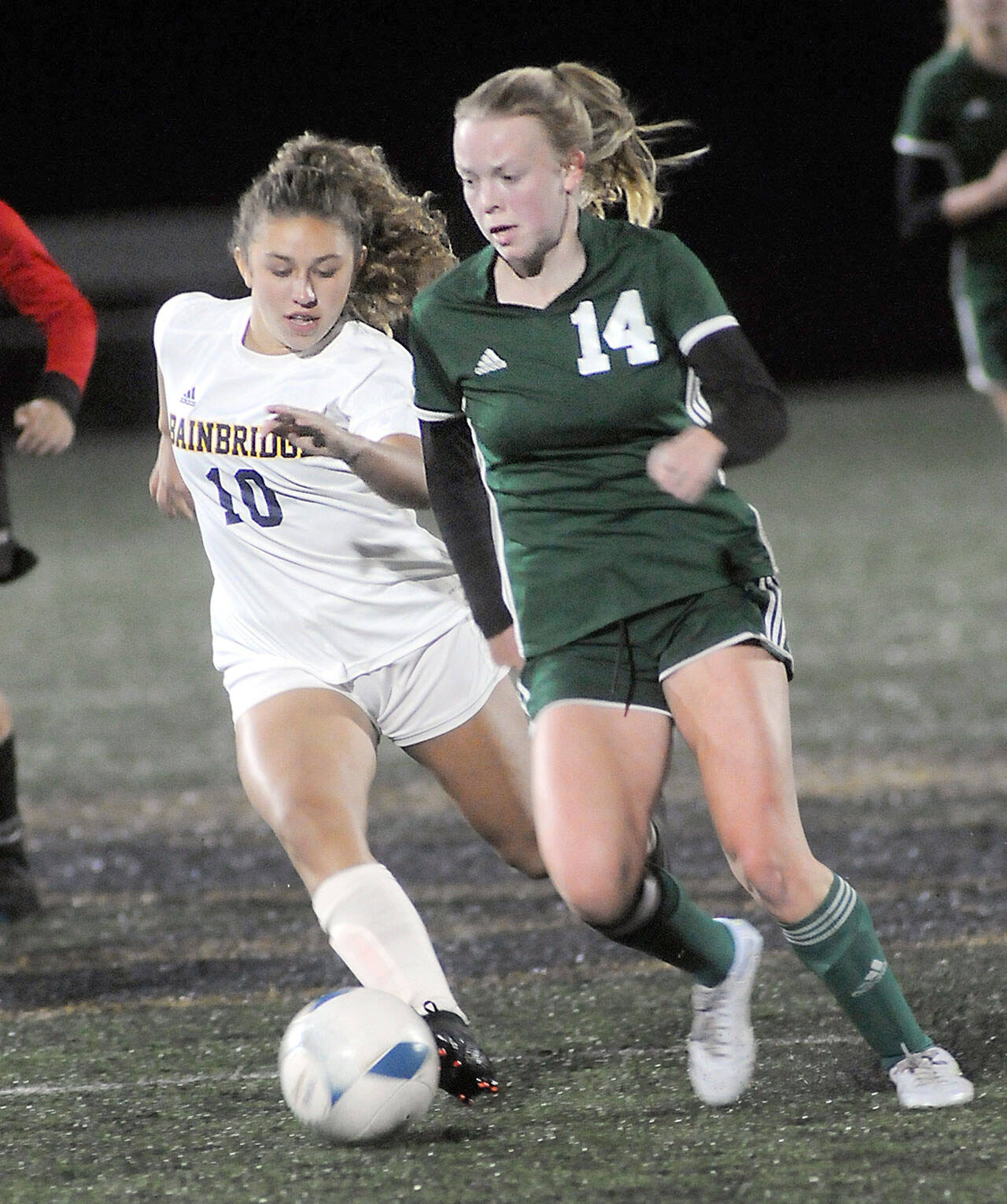 Port Angeles’ Anna Petty, right, races past Bainbridge’s Sophia Weindl during Tuesday’s match at Wally Sigmar Field in Port Angeles. (Keith Thorpe/Peninsula Daily News)