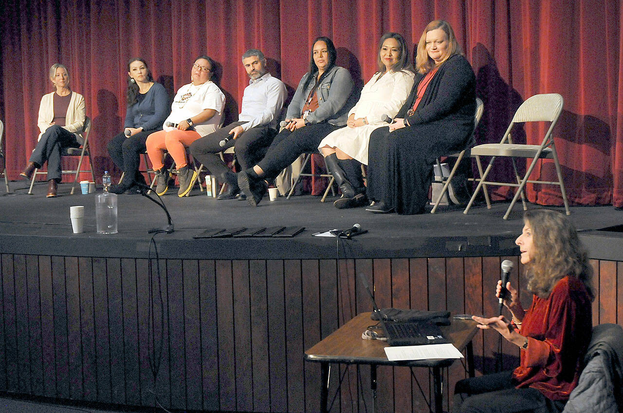 Kate Reavey, English instructor and Studium Generale coordinator for Peninsula College, lower right, gives an introduction to a panel discussion on the Indian Child Welfare Act and its impact on Native peoples as part of the college’s Studium Generale series on Thursday on the school’s Port Angeles campus. Included on the panel were, from left, Dustin Brenske, behavioral health specialist with the Jamestown S’Klallam Tribe; Jessica Humphries, education services supervisor with Jamestown S’Klallam; Charlotte Penn, crime victims services program manager with the Quileute Tribe; Brandon Mack, family court commissioner for Clallam County Superior Court; Vashti White, ICW case manager with the Lower Elwha Klallam Tribe; Joylina Gonzalez, child welfare program manager with the Port Gamble S’Klallam Tribe; and Rachel Munoz-McCormick, Clallam County Court facilitator. (Keith Thorpe/Peninsula Daily News)