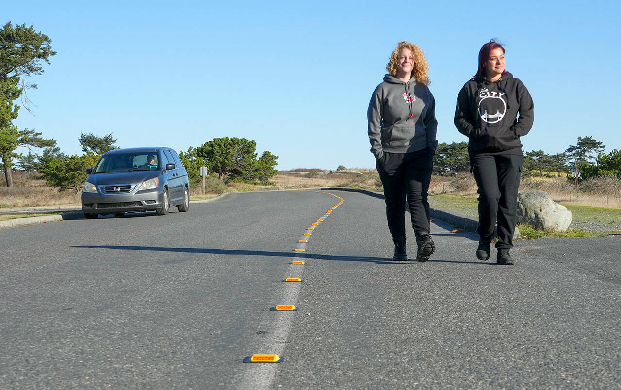 Danielle Osmum, left, and Dina Concepion, both from Las Vegas, walk safely along the newly defined pedestrian, bike and handicapped lane on Harbor Defense Way at Fort Worden State Park earlier this month. The markers were paid for by the Friends of Fort Worden by a donation of one of their members. The new installation is expected to last at least 10 years or longer. (Steve Mullensky/for Peninsula Daily News)