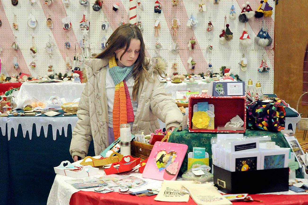 Mia Hampton, 9, of Port Angeles examines a table filled with holiday gifts on Friday at the annual Christmas Cottage craft fair at Vern Burton Community Center, 308 E. Fourth St. in Port Angeles. The fair, which continues from 9 a.m. to 6 p.m. today and from 10 a.m. to 4 p.m. Sunday, features a wide variety of locally produced handcrafted items and baked goods for the holiday season. (Keith Thorpe/Peninsula Daily News)