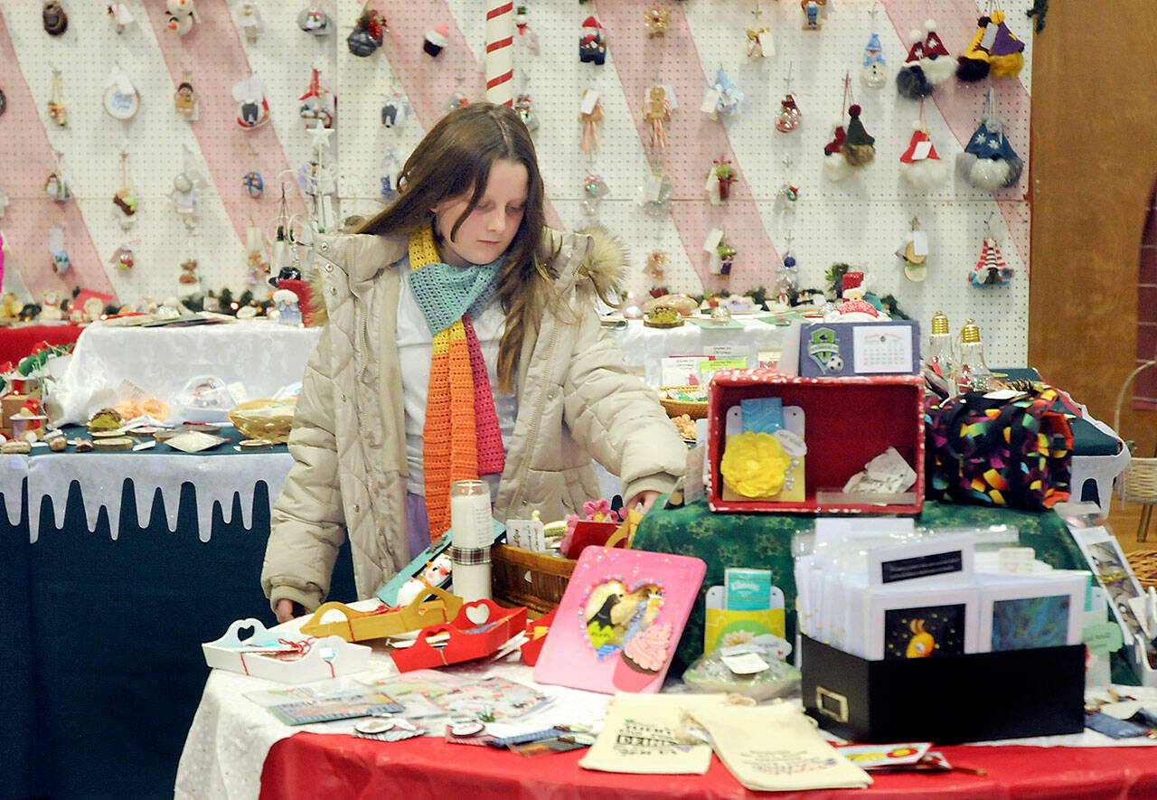 Mia Hampton, 9, of Port Angeles examines a table filled with holiday gifts on Friday at the annual Christmas Cottage craft fair at Vern Burton Community Center, 308 E. Fourth St. in Port Angeles. The fair, which continues from 9 a.m. to 6 p.m. today and from 10 a.m. to 4 p.m. Sunday, features a wide variety of locally produced handcrafted items and baked goods for the holiday season. (Keith Thorpe/Peninsula Daily News)