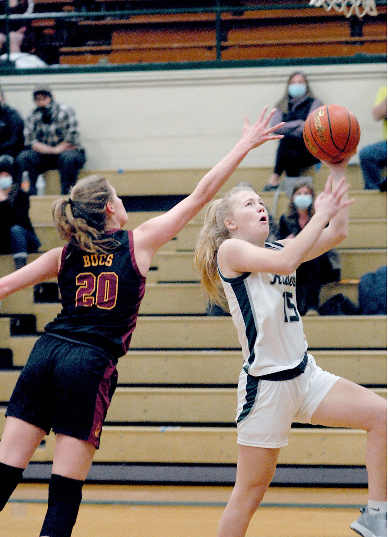 Port Angeles’ Paige Mason, right, looks of the layup as Kingston’s Ellee Brockman defends the lane on Thursday night at Port Angeles High School. (Keith Thorpe/Peninsula Daily News)