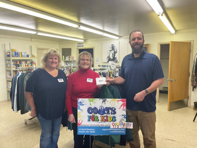 Coats For Kids organizers Karen Lewis and Heidi Albrecht present Levi Douglas, Clallam County Veterans Program Coordinator, with more than $1,200 worth of certificates for veterans at the Northwest Veterans Resource Center.