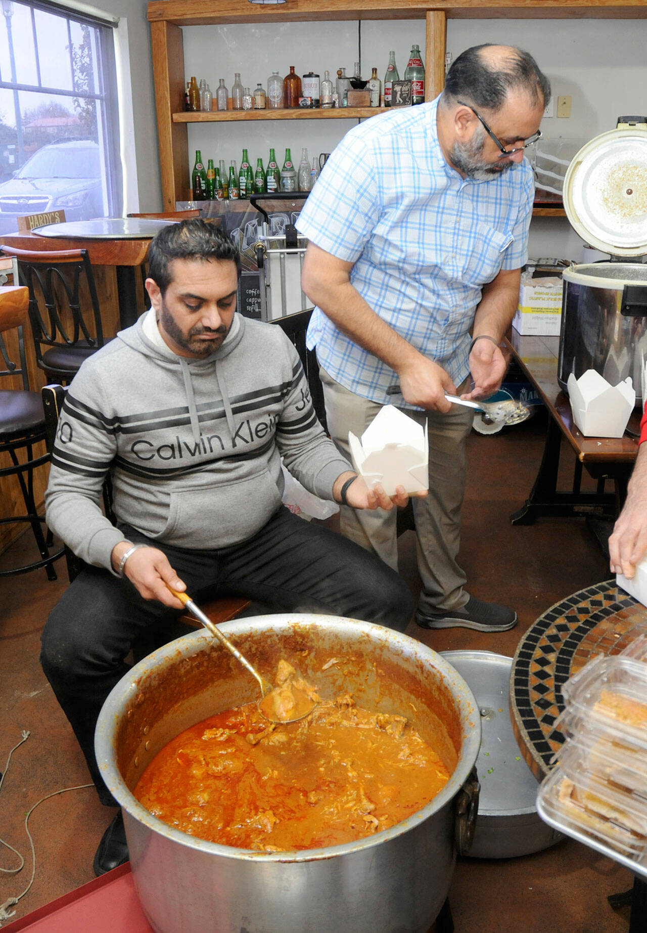 Harry Nagra, left, and Harry Sangha, owners of Hardy’s Market in Sequim, dish out dinner boxes of Biryani chicken and rice for the market’s annual Thanksgiving Day meal giveaway. The meals also included slices of pumpkin pie for distribution to hungry diners. (Keith Thorpe/Peninsula Daily News)